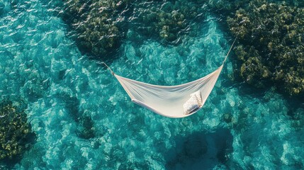 Top view of a Maldives hammock suspended over the ocean, with gentle waves beneath and a clear sky above.