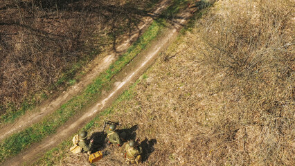 Men Dressed As US American Soldiers Of USA Infantry Of World War II sneaking around In spring Autumn Day. Soldiers prepare mortar for battle In dry grass. Aerial view elevated shot