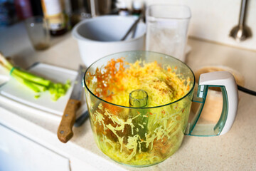 Grated raw vegetable (potato,carrot,zucchini) on big bowl on kitchen board.