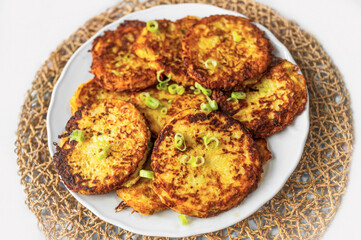 Fried salty pancake from potato, carrot and zucchini on white plate.
