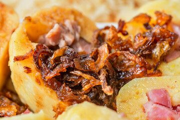 Sliced boiled dumpling with smoked meat piece and golden crispy fried onion.