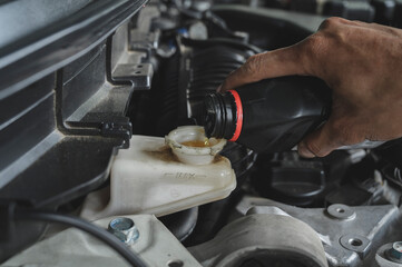 Auto mechanic Topping up brake fluid in brake fluid reservoir.