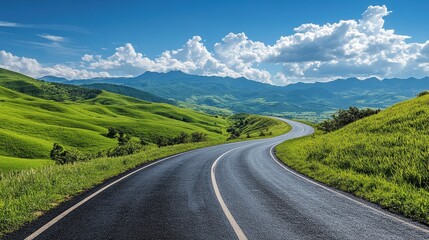 Fototapeta premium Winding Road Through Lush Green Hills Under a Bright Blue Sky with White Clouds