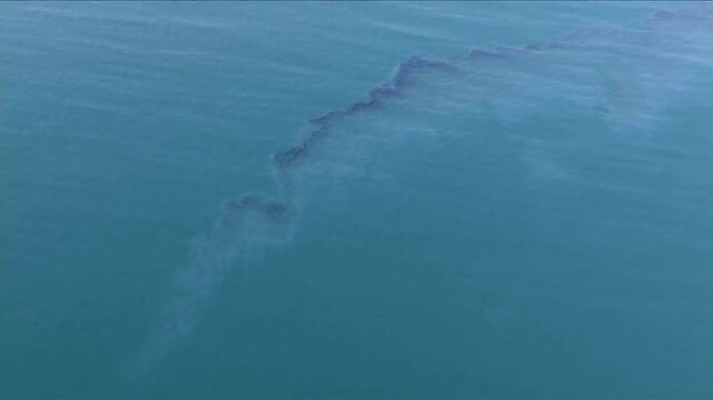 DRONE VIEW OF LARGE FLOATING OIL SPILL IN THE OCEAN