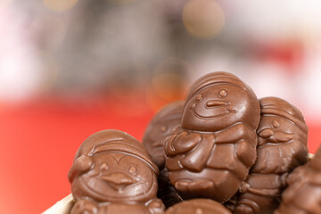 Chocolates in the shape of Christmas figures in the wooden box on the red background