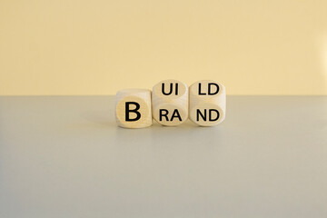 Build your brand symbol. Concept words Build brand on wooden cubes. Beautiful beige background, gray table. Build your brand and business concept.