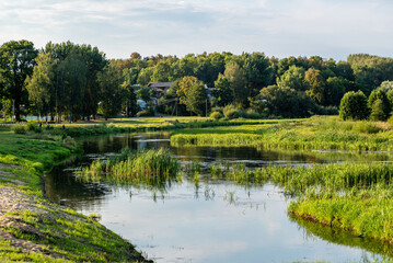 Evening landscape of a river, green grass and trees in the vicinity of the town of Vileika