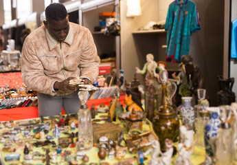 Ordinary Afro-American guy considers things sacond hands on flea market