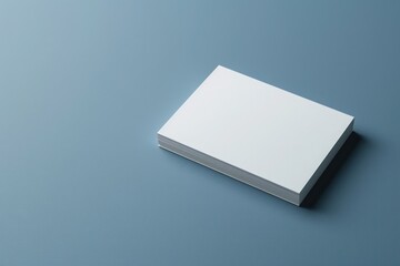 A refined real estate agents business card rests on a smooth blue surface, showcasing a minimalist design perfect for capturing client interest in a contemporary setting.