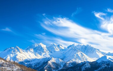 Obraz premium Stunning snow-capped mountains under a vibrant blue sky with wispy clouds creating a breathtaking landscape.