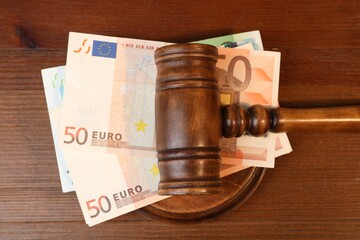 Alimony. Money between judge's gavel and sound block on wooden table, top view