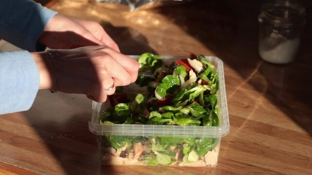 Woman hands stirring a tupper salad in rustic kitchen. Real people. Healthy food.
