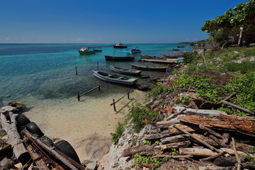 Small wood fishing boats moored to wooden stakes in the lagoon within the coral reef next to Cabo...