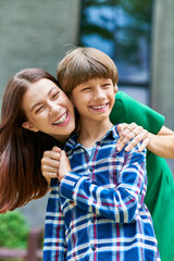 Fototapeta premium A mother embraces her hearing impaired son, both sharing laughter and joy together.