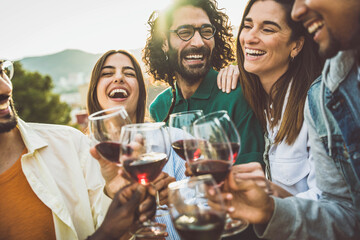 Happy friends toasting red wine glasses outside - Group of young people having bbq dinner party in backyard house - Winery and bbq dining concept with guys and girls cheering alcohol together