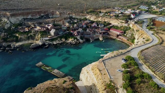 Charming 4K drone footage showcasing the colorful Popeye Village in Malta. Discover this iconic seaside village from above, a beloved tourist attraction and film set