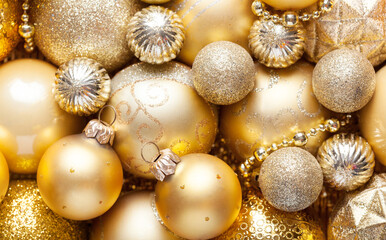 Christmas Holiday background with shiny golden baubles, ornaments. Close up of pile golden Christmas decorations different sizes, shades and textures. Top view