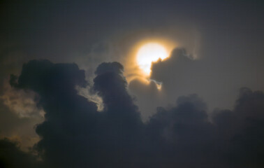 Sun disk behind dark clouds at sunset