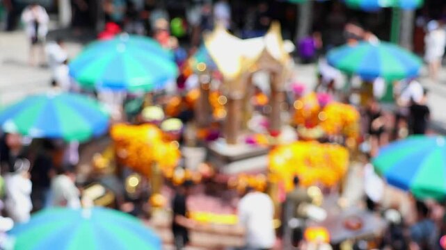 Bokeh view of blurred Erawan Shrine at Ratchaprasong Intersection. Local people and tourists come to worship and pay respect to the Phra Phrom, Bangkok, Thailand.