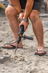 Industrial tool for repairing paving stones on the sidewalk. A man removes old cobblestones with a perforator. Drill, shovel, pickaxe and hammer on construction site. Road repair. Home tool.