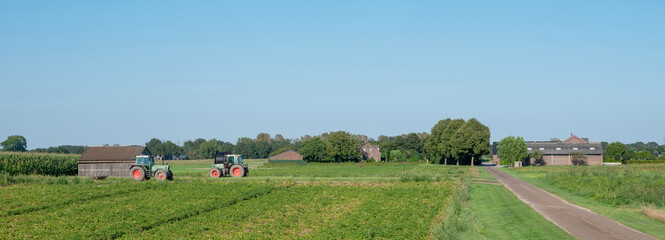 dead end country road with field and tractors in national park maasduinen