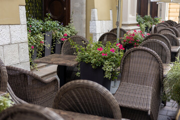 Furniture on the terrace in a cafe on the square with a beautiful interior and blooming flowers in the city, morning time