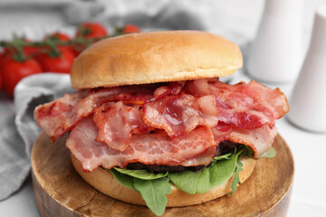 Delicious burger with bacon and greens on table, closeup