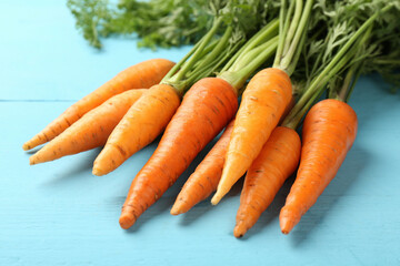 Tasty ripe juicy carrots on light blue wooden table, closeup