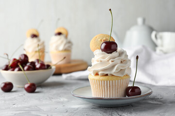 Delicious cupcake with cherries and cookies on grey textured table