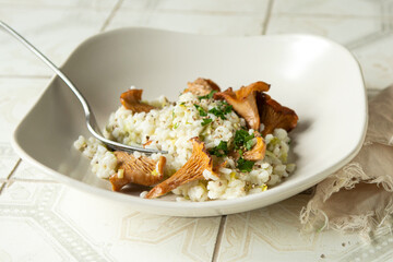 plate of risotto with chanterelles on light table