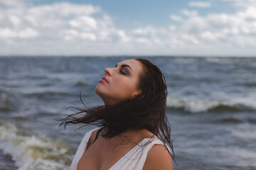 banner, portrait of brunette woman in profile looks to right with wet flying hair against background of sea