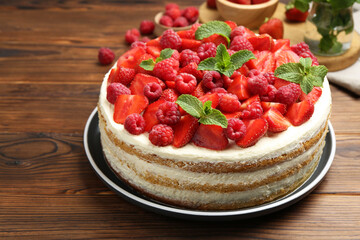 Tasty sponge cake with fresh berries and mint on wooden table, closeup