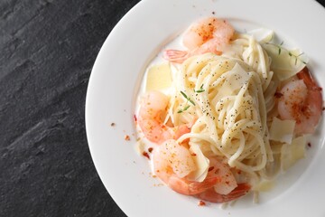 Delicious pasta with shrimps and cheese on black table, top view