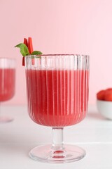 Tasty watermelon drink in glass and mint on white wooden table, closeup