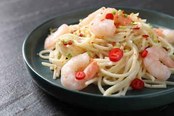 Delicious pasta with shrimps, green onion and chili pepper on black table, closeup