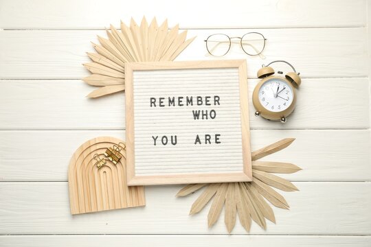 Naklejki Flat lay composition of letter board with phrase Remember Who You Are on white wooden table