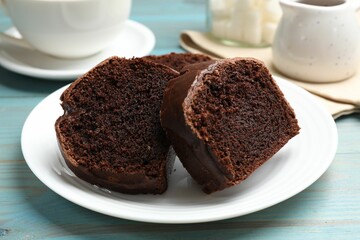 Slices of tasty chocolate sponge cake on light blue wooden table, closeup
