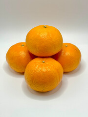 A clean, bright image of fresh oranges stacked in a simple pyramid arrangement on a pure white background. The vivid orange color of the fruit contrasts with the minimalist backdrop.