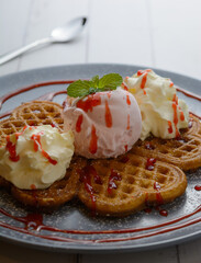 Waffles topped with ice cream and strawberry jam on white table background, Close-up of Homemade waffles.