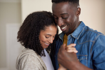 Affectionate young multiracial couple smiling and dancing together at home
