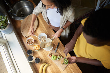 Young multiracial couple preparing a healthy fruit and oats breakfast