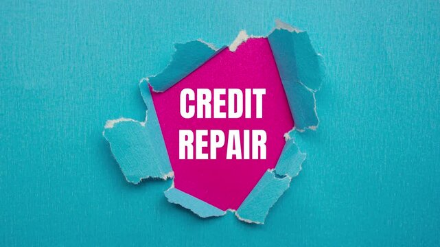 Credit repair message writing on ripped torn blue paper on pink background. Conceptual credit repair symbol.
