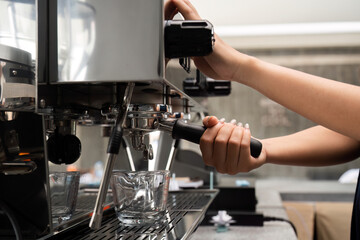 Young Barista Skillfully Preparing Coffee with Espresso Machine in Modern Cafe Setting