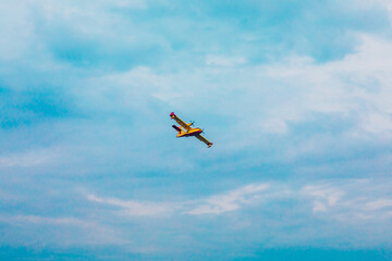 Small airplane. Yellow red Propeller plane is flying on blue sky