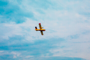 Small airplane. Yellow red Propeller plane is flying on blue sky