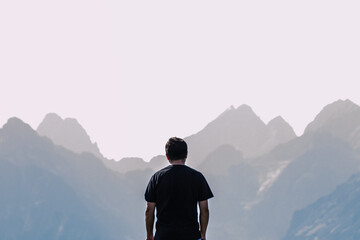 mężczyzna na tle gór patrzy na szczyty, Tatry Wysokie, grań Tatr w tym Rysy, turysta na Rusinowej Polanie