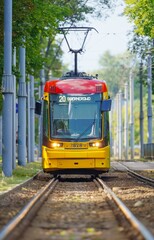 Naklejka premium The image features a modern yellow and red tram on a bustling streetof Warsaw. The tram is sharply in focus against a blurred background, emphasizing its vibrant colors and creating a dynamic sense of
