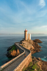 Petit Minou lighthouse and its headland, aerial view at sunset with a woman walking through the bridge