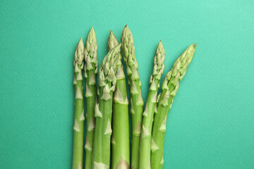 Fresh green asparagus stems on turquoise table, top view
