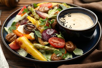 Delicious salad with grilled vegetables and sauce on table, closeup